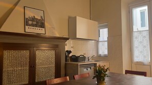 A kitchen with a dining table, a potted plant, and a framed picture of Bergamo, Italy. - 'Papavero Piazza Delfino' Apartment with Balcony and Wi-Fi (Bergamo)