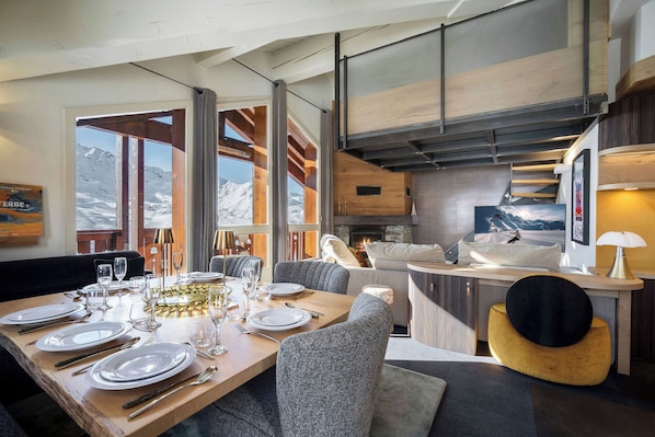 A modern dining area with a wooden table set for a meal, a sofa, and a fireplace.