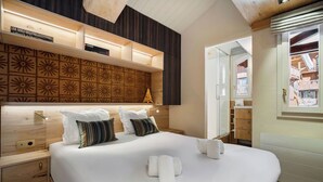 Une chambre d’hôtel avec un grand lit, une tête de lit en bois, des étagères intégrées, un petit sapin de Noël et une vue sur l’intérieur de l’hôtel.