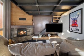 A modern living room with a fireplace, a flat-screen TV, and a cozy seating area.
