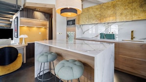 Une cuisine moderne avec un îlot en marbre, des armoires en bois et des tabourets de bar.