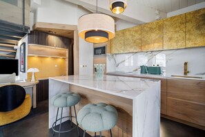 A modern kitchen with a marble island, wooden cabinets, and bar stools.