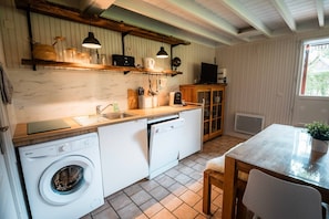 A compact kitchen with a washing machine, a sink, a wooden table, and a cabinet.
