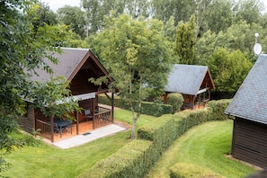 Two wooden cabins with porches, surrounded by well-maintained lawns and dense trees.