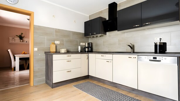 A modern kitchen with a dishwasher, coffee maker, and a clock on the wall.