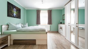 A bedroom with a bed, bedside table, wardrobe, and a window with curtains.