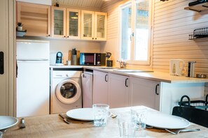 Une cuisine compacte équipée d’un lave-linge, d’un four à micro-ondes et d’un coin repas avec une table dressée pour deux personnes.