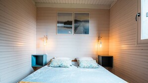 Ein Schlafzimmer mit einem Bett, zwei Wandlampen und zwei gerahmten Bildern an der Wand.