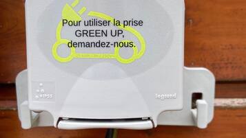 Une boîte électrique grise avec les inscriptions « green up » et « Pour utiliser la prise GREEN UP, veuillez nous contacter ».