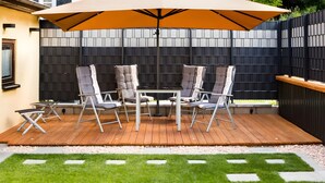 A patio with a table and chairs, a large umbrella, and a black fence.