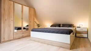 A bedroom with a bed, bedside tables, a wardrobe, and a mirror.