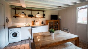 Una cocina funcional con lavadora, una mesa de madera y un armario.
