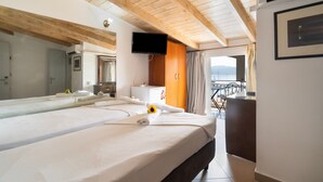 Ein Hotelzimmer mit einem großen Bett, einem Fernseher, einem Schreibtisch und einem Balkon mit Blick.