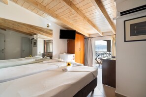 Ein Hotelzimmer mit einem großen Bett, einem Fernseher, einem Schreibtisch und einem Balkon mit Blick.