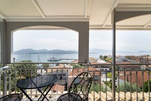 Ein Balkon mit Blick auf das Meer, Boote und ferne Berge.