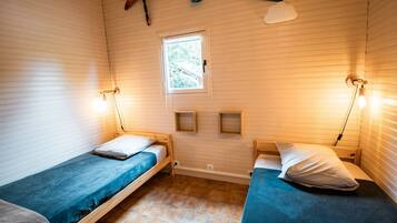 Ein Zimmer mit zwei Holzkamabetten, einem kleinen Fenster und Wandregalen.