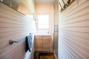 Un baño estrecho con ventana, un lavabo y un perchero para toallas.