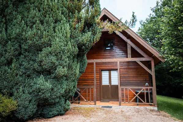 Eine Holzhütte mit Veranda, umgeben von dichten Nadelbäumen.