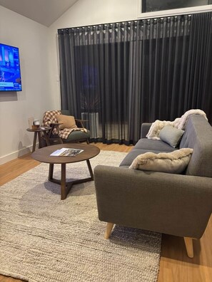 A living room with a sofa, a coffee table, a TV, and a window with curtains. - 'Cascade' at Small Batch (Budgee Budgee)