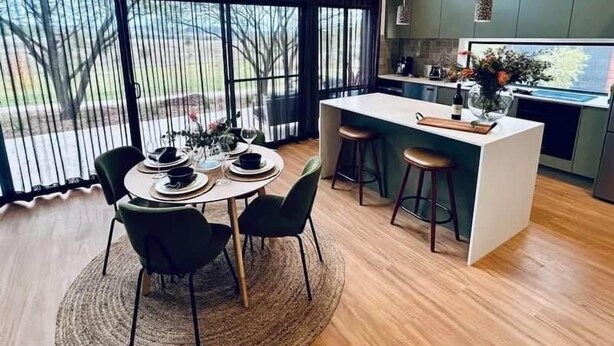Een moderne keuken met een centraal eiland, barstoelen en een eethoek met een ronde tafel en stoelen.