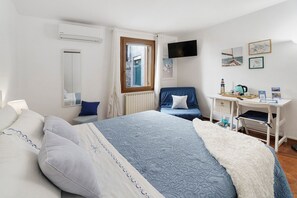 Una camera da letto con un letto, una scrivania, una sedia, una televisione e opere d'arte alle pareti.
