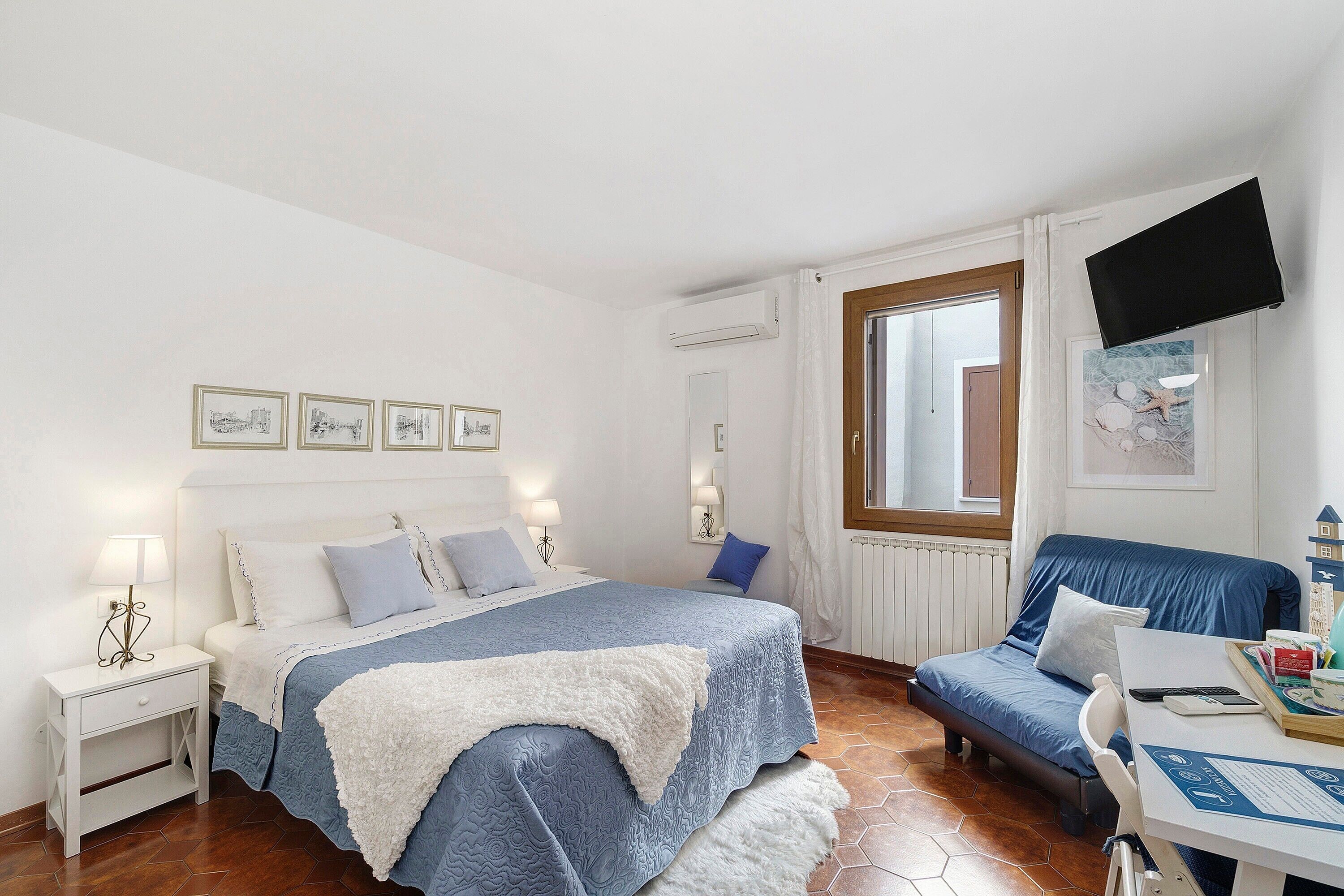 Une chambre à coucher comprenant un lit, des tables de chevet, un bureau et un téléviseur.