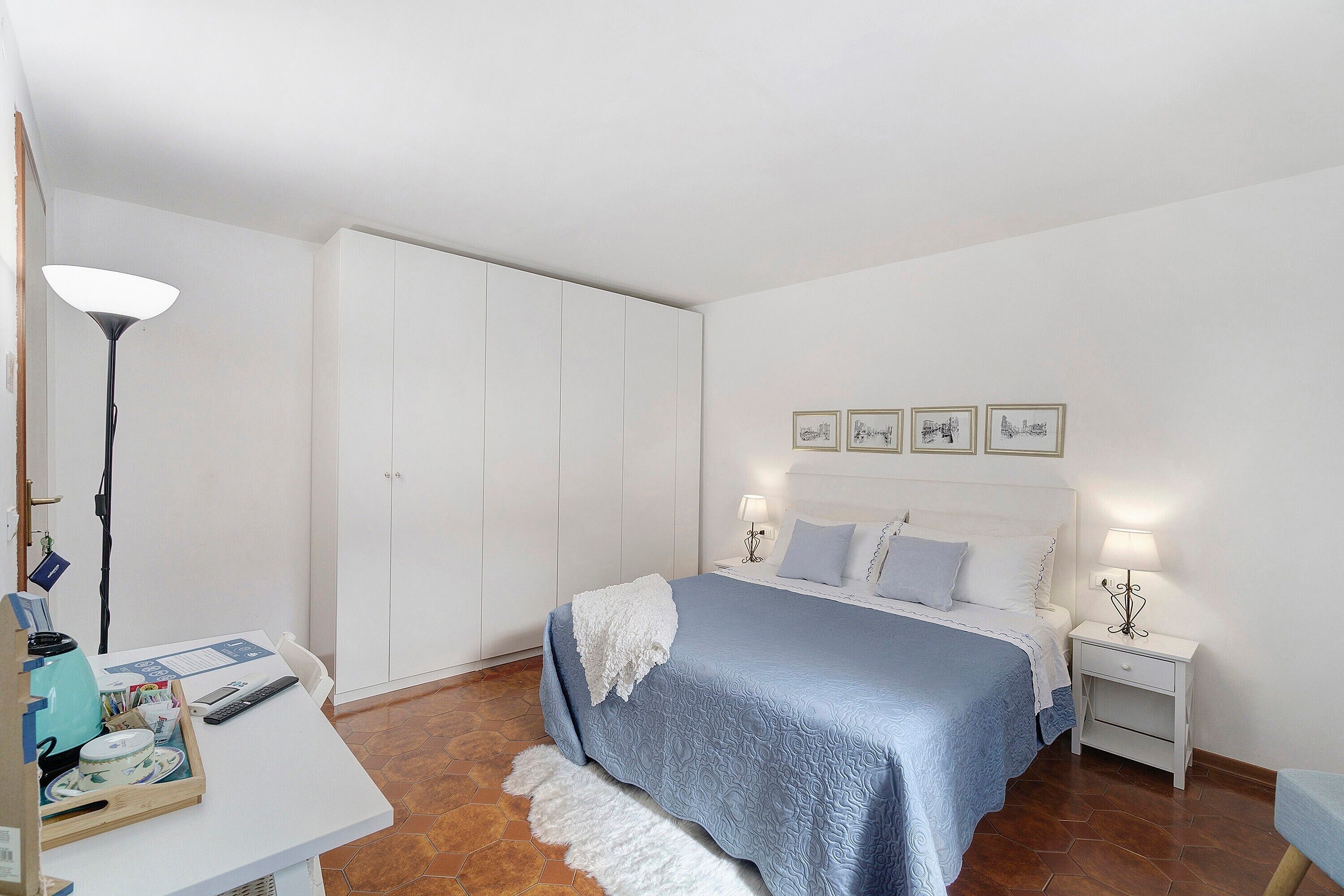 Un dormitorio con cama, mesitas de noche, un escritorio y un armario.