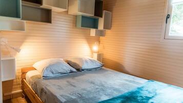 Une chambre à coucher comprenant un lit, des tables de chevet, une commode et des étagères intégrées.