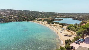 Eine Küstenlandschaft mit Strand, klarem Wasser und hügeliger Kulisse.