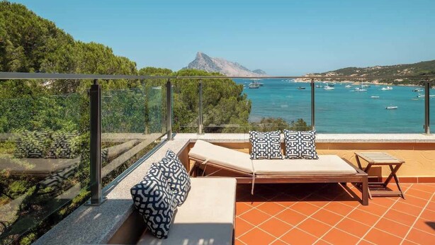 Ein Balkon mit Meerblick, eine Sitzecke mit Kissen und ein kleiner Tisch.