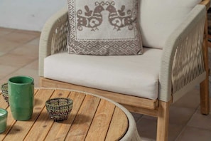 A wicker chair with a cushion, a round wooden table with green and patterned bowls, and a green vase. - Villa Ninfea - sea view and relax (Aldia Bianca)