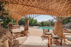 A poolside area with a thatched roof, lounge chairs, and a view of the pool and surrounding landscape. - Villa Ninfea - sea view and relax (Aldia Bianca)