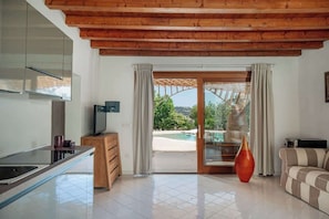 A modern kitchen with a glass island, wooden ceiling, and a view of a pool. - Villa Ninfea - sea view and relax (Aldia Bianca)