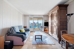 Un salon avec un canapé, une table en bois, un meuble et une vue à travers une porte vitrée.