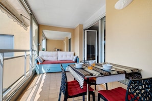 Een balkon met een eettafel, stoelen en een bank.