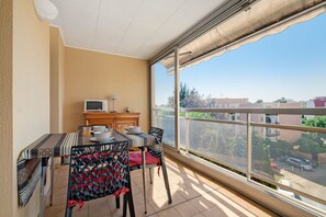Un balcon avec une table, des chaises, un téléviseur et une vue sur la ville.