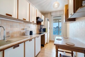 Een moderne keuken met witte kastjes, een roestvrijstalen spoelbak en een houten tafel.