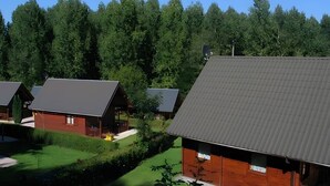 Una hilera de cabañas con techos inclinados, rodeadas de un bosque frondoso.