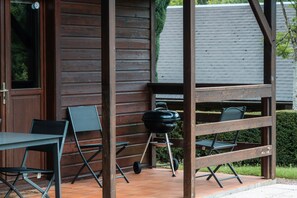 Eine Holzkonstruktion mit Grill, Klappstühlen und Tisch.
