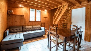 Un interior de madera con sofá, mesa de comedor, sillas y una escalera.