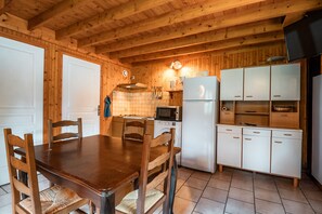 Un interior de madera con una mesa de comedor, sillas, microondas, refrigerador y un armario.