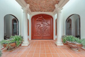 A building entrance with a large wooden door, two columns, and potted plants. - Cerca del Mar – Beachfront, Sleeps 10, Rocky Point (Puerto Peñasco)