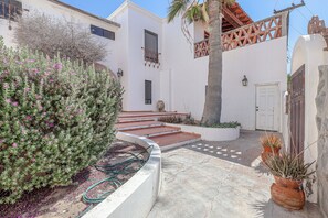 Une cour avec un bâtiment blanc, des marches menant à une porte et des plantes en pot.