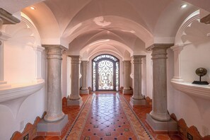 A hallway with a tiled floor, columns, and a decorative door. - Casa Elegante – Ocean View Estate, Rocky Point (Puerto Peñasco)