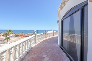 Un balcon avec vue sur la mer, un sol carrelé et une balustrade blanche.