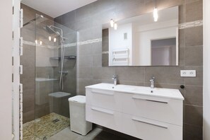 A modern bathroom with a glass-enclosed shower, a white vanity with drawers, and a large mirror. - Apartment 'T2 Stunning Sea View' with Sea View, Wi-Fi and Air Conditioning (Cagnes-sur-Mer)