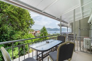 A balcony with a table and chairs, overlooking a body of water and greenery. - Room 'Quadruple  401' with Sea View, Wi-Fi and Air Conditioning (Nikiana)