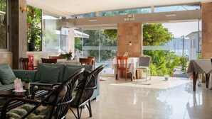 A spacious indoor area with a dining table, chairs, and a sofa. - Room 'Quadruple  401' with Sea View, Wi-Fi and Air Conditioning (Nikiana)