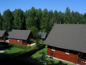 A row of cabins with sloped roofs, surrounded by dense forest. - Chalet Noël des Champs for 8 with Shared Pool, Terrace, and Wi-Fi (Livarot-Pays-d'Auge)