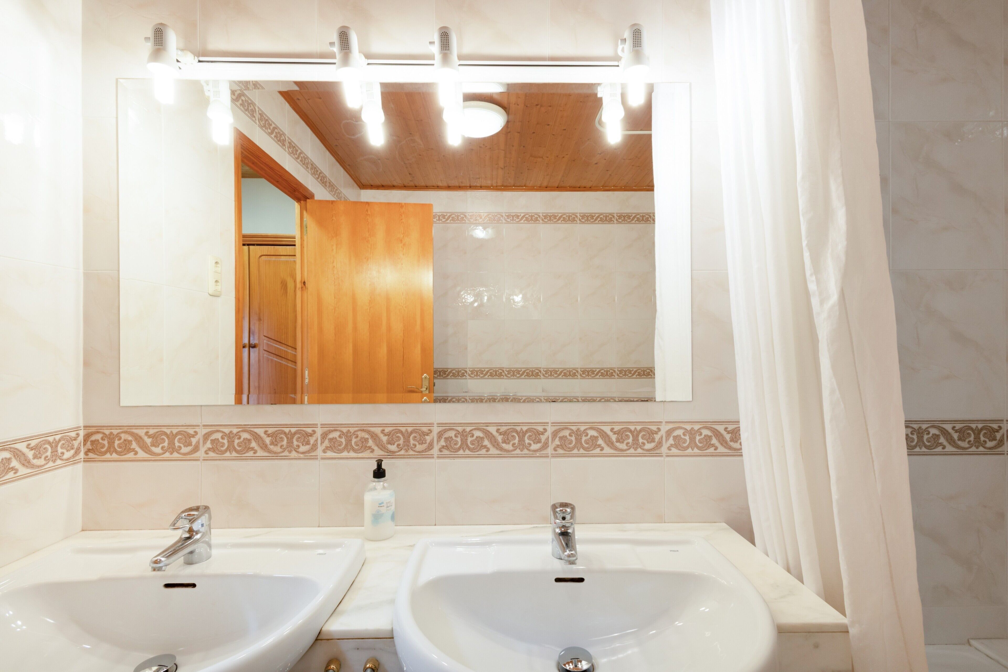 A bathroom with two sinks, a mirror, and a shower curtain.